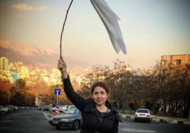 A young Iranian woman waves a white headscarf 